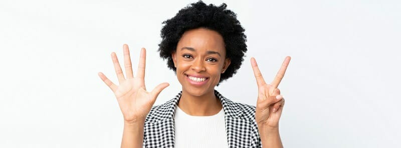 African american woman with blazer over isolated white background counting seven with fingers