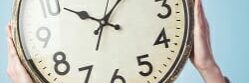 portrait of a business young woman holding a clock in front of her face